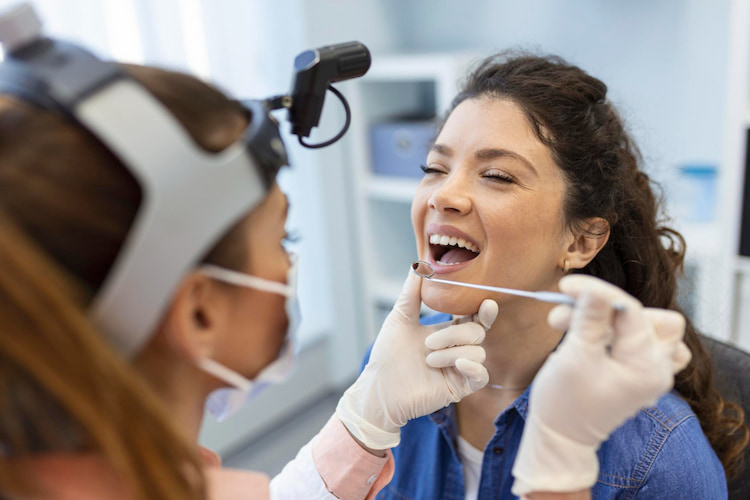 a woman's teeth are being checked by a dentist to prevent cavities.