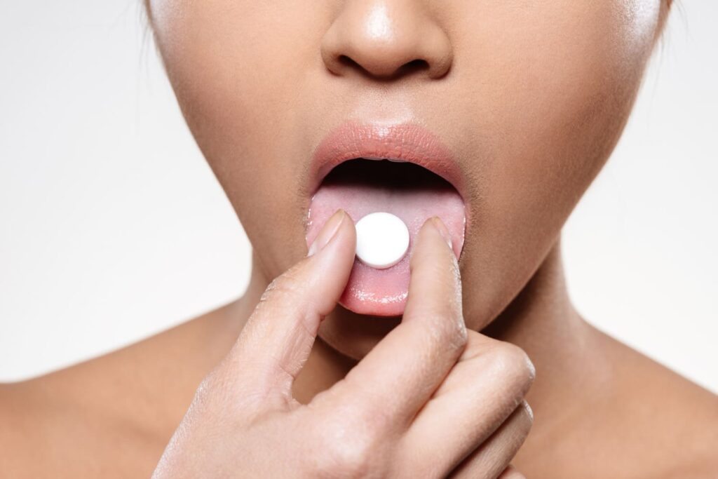 a woman  putting a tablet on her mouth